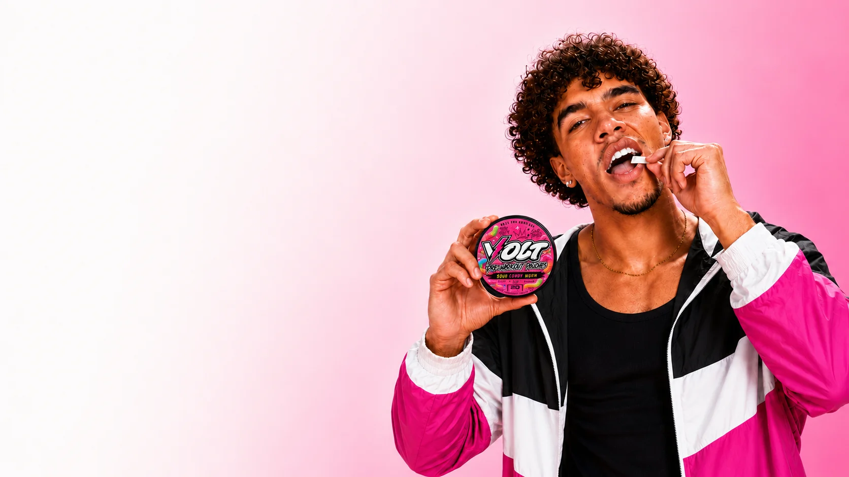 Athlete in a pink, blue and white windbreaker placing a VOLT Sour Gummy Worm pouch in his lip while holding the can